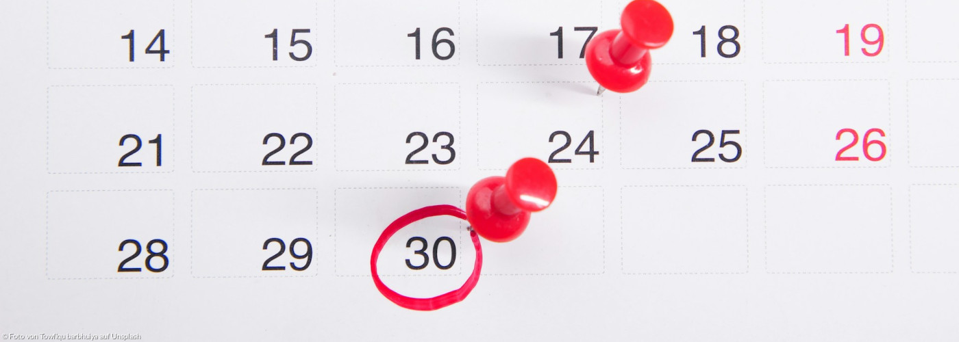Ein Kalender mit daran angehefteten roten Druckknöpfen