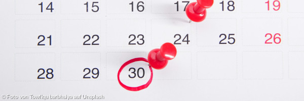 Ein Kalender mit daran angehefteten roten Druckknöpfen